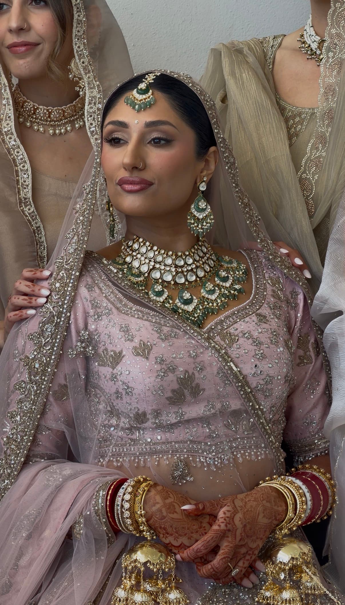 South Asian bride in pink lehenga with gold jewelry